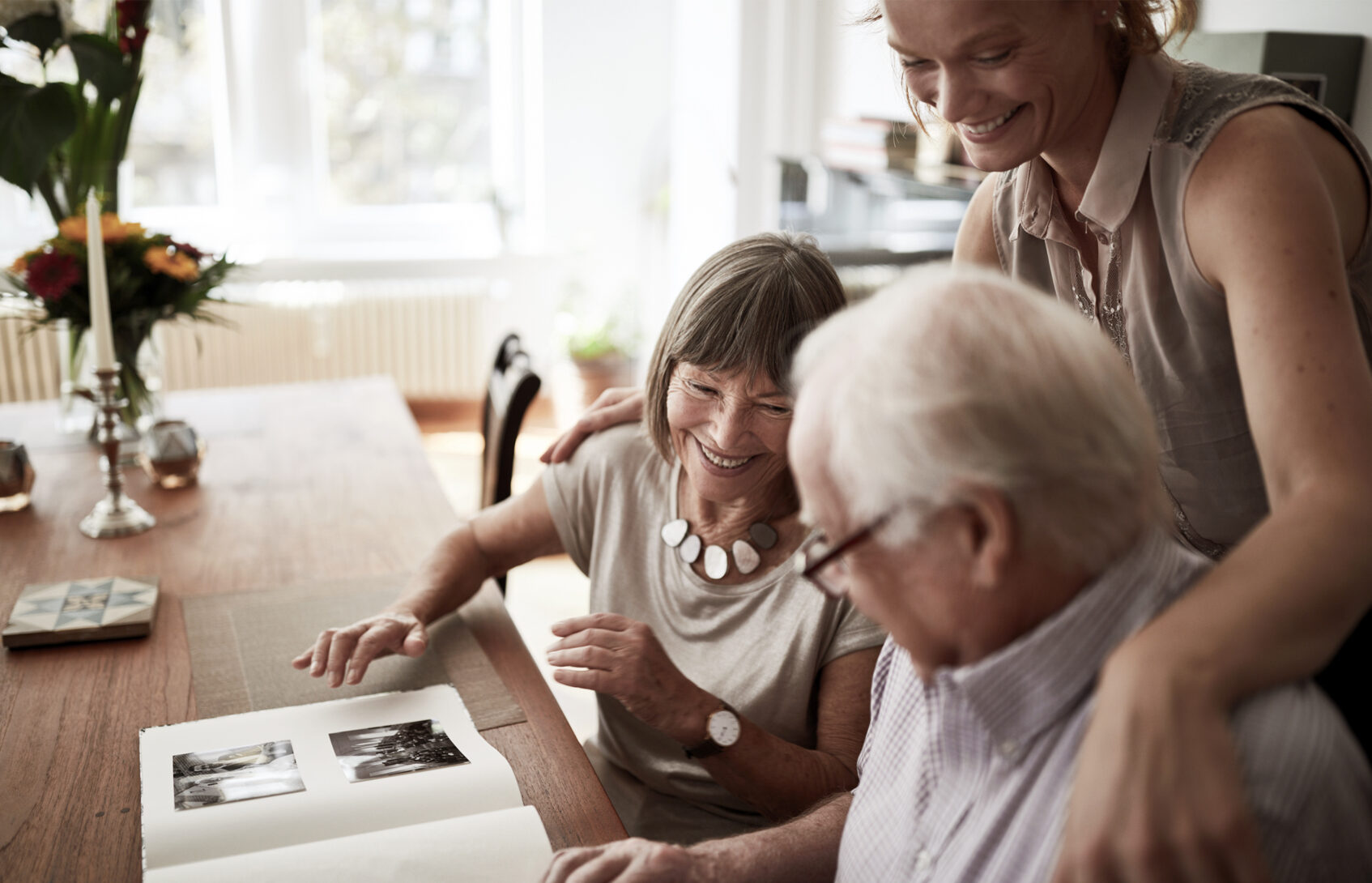 A family of three looking at a photo album on a desk.