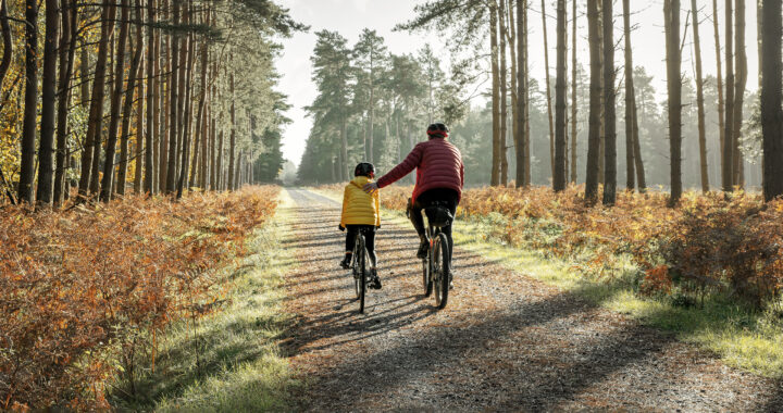 A young girl and father cycling in the forest.