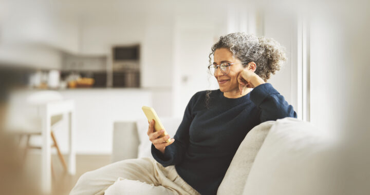 A happy woman sitting on the couch, looking at her phone