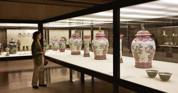 A woman views a series of floral urns at a museum exhibition